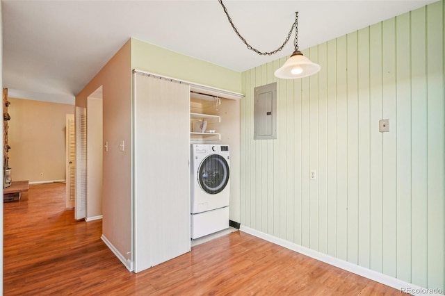 washroom with laundry area, wood finished floors, baseboards, electric panel, and washer / dryer