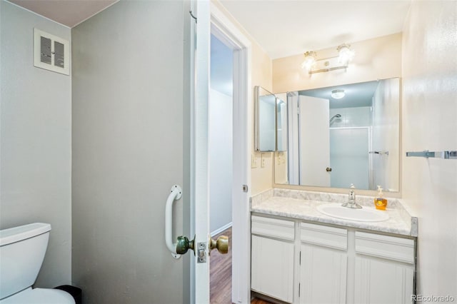 bathroom featuring visible vents, vanity, toilet, and walk in shower