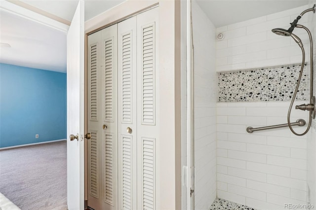 bathroom with a closet, a shower stall, and baseboards