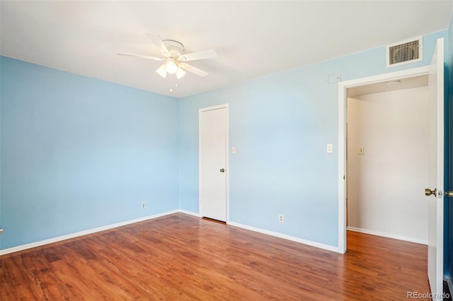 spare room with ceiling fan, wood finished floors, visible vents, and baseboards