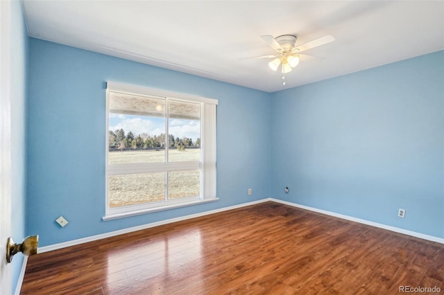 unfurnished room featuring ceiling fan, dark wood-type flooring, and baseboards