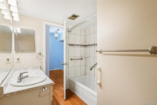 bathroom with washtub / shower combination, visible vents, vanity, and wood finished floors