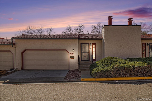 view of front facade featuring stucco siding, concrete driveway, a tile roof, and a garage