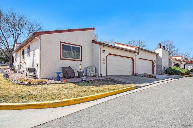 view of front of home with stucco siding, driveway, a front yard, and an attached garage