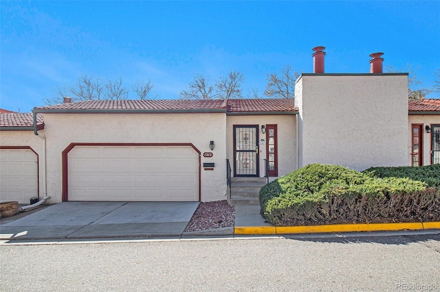 view of front of home featuring stucco siding, a garage, concrete driveway, and a tiled roof