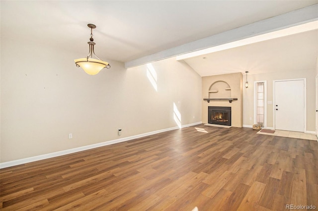 unfurnished living room with a glass covered fireplace, lofted ceiling with beams, baseboards, and wood finished floors