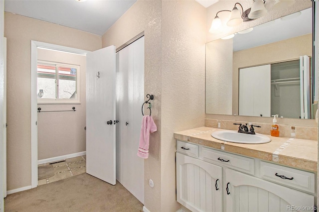 bathroom with vanity, baseboards, and a textured wall