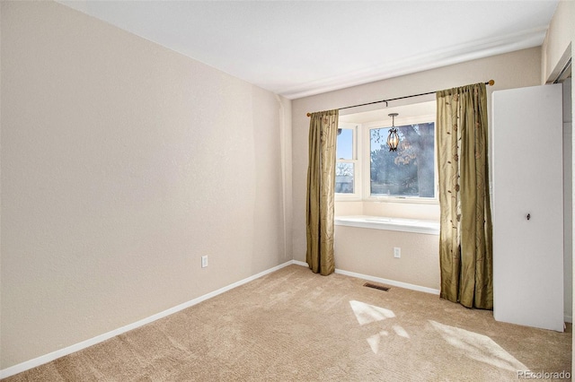 empty room with light carpet, visible vents, and baseboards