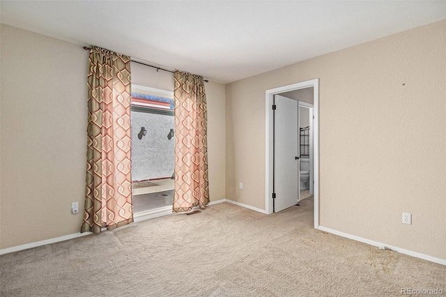 unfurnished room featuring carpet, baseboards, and a textured wall