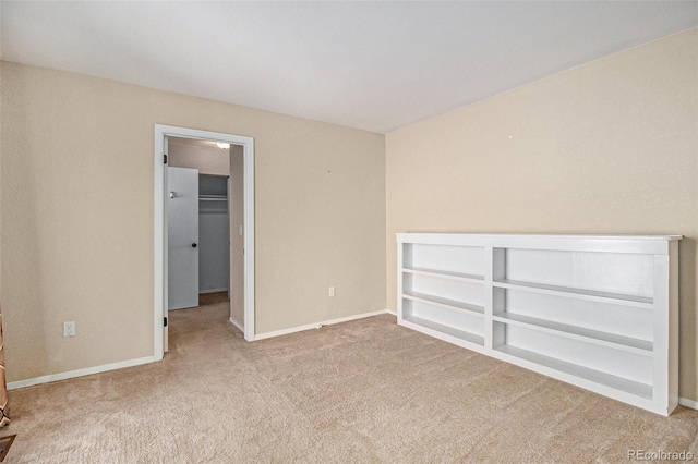 unfurnished bedroom with a closet, baseboards, a spacious closet, and carpet flooring