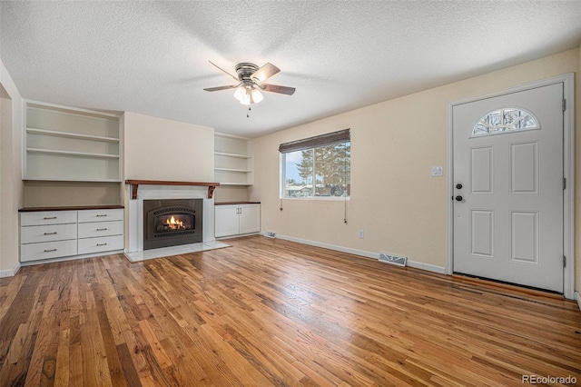 unfurnished living room featuring ceiling fan, a textured ceiling, and light hardwood / wood-style flooring