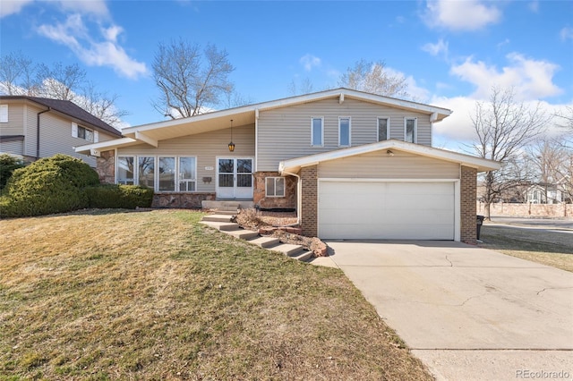 split level home featuring brick siding, a garage, driveway, and a front yard