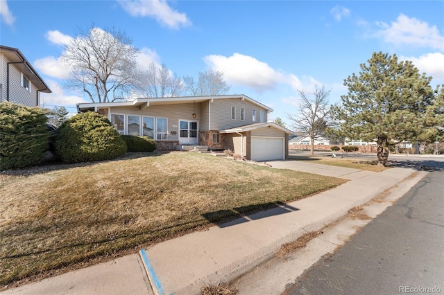 view of front of property with brick siding, an attached garage, concrete driveway, and a front yard