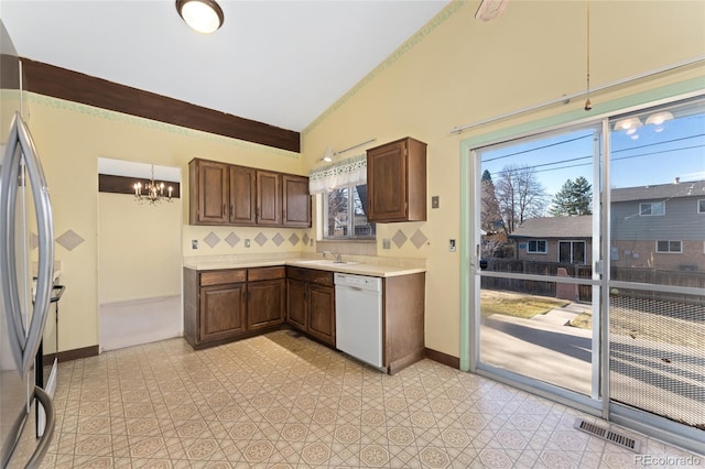 kitchen with visible vents, stainless steel refrigerator, a sink, white dishwasher, and light countertops