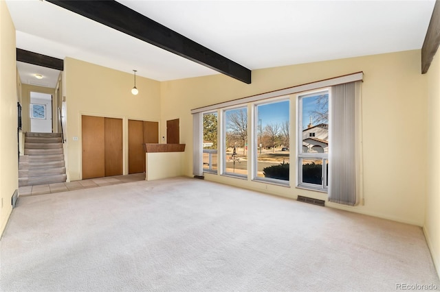 carpeted empty room with lofted ceiling with beams, visible vents, and stairs