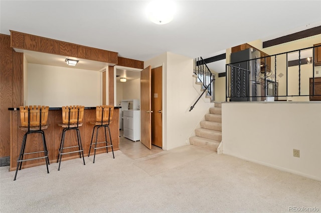 below grade area with a bar, wooden walls, stairs, and carpet