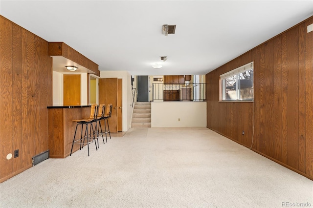 spare room featuring carpet, wood walls, stairs, and a bar