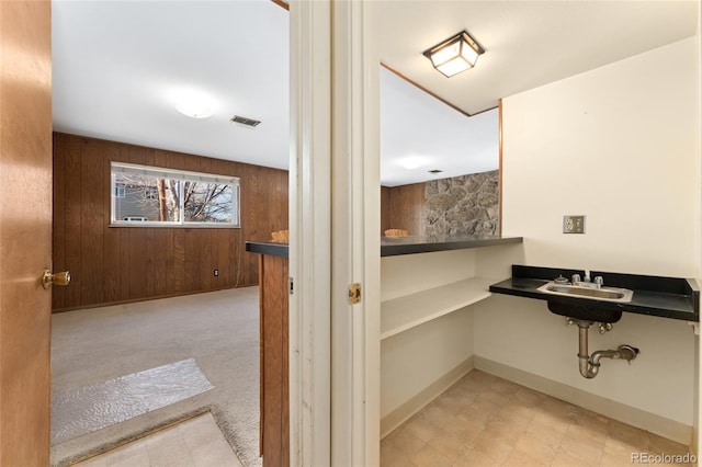 bathroom with a sink, visible vents, baseboards, and wooden walls