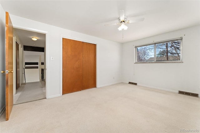 unfurnished bedroom featuring a closet, visible vents, light colored carpet, and baseboards