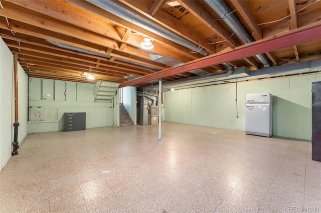 unfinished below grade area with tile patterned floors, refrigerator, heating unit, and stairway