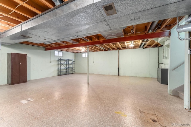 below grade area featuring tile patterned floors, visible vents, and stairs