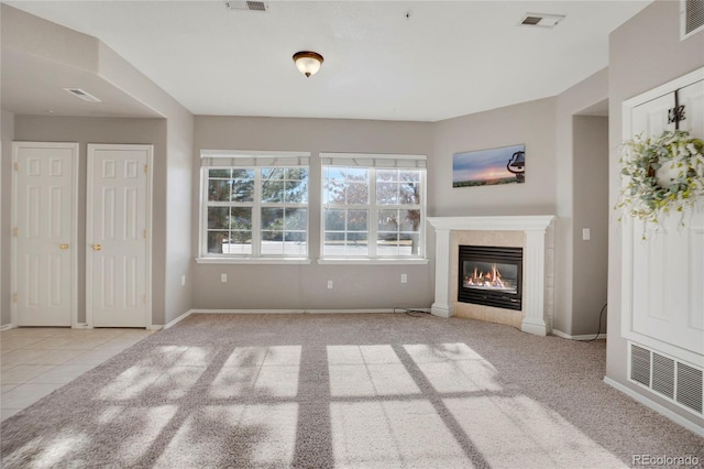 unfurnished living room with a glass covered fireplace, visible vents, and baseboards