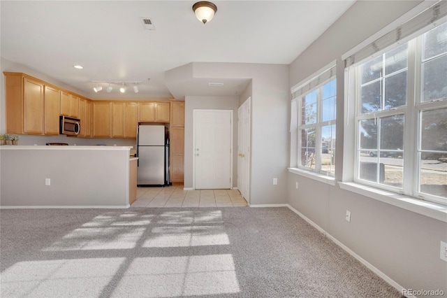 kitchen with visible vents, baseboards, light colored carpet, stainless steel appliances, and light brown cabinets