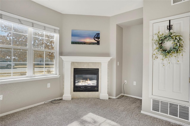 unfurnished living room featuring carpet floors, a tiled fireplace, visible vents, and a healthy amount of sunlight