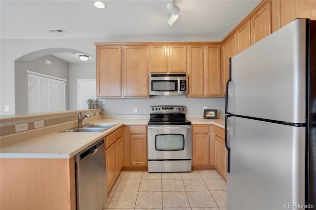 kitchen featuring light tile patterned floors, stainless steel appliances, a peninsula, a sink, and visible vents