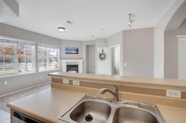 kitchen with visible vents, a glass covered fireplace, open floor plan, light countertops, and a sink