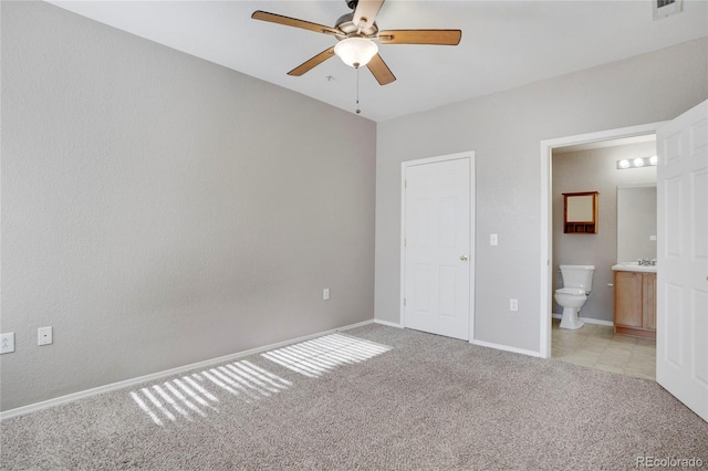 unfurnished bedroom featuring light colored carpet, visible vents, ensuite bathroom, a ceiling fan, and baseboards