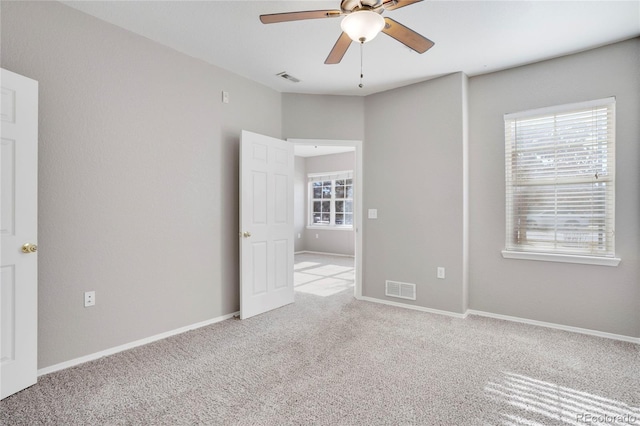 unfurnished bedroom with carpet floors, a ceiling fan, visible vents, and baseboards