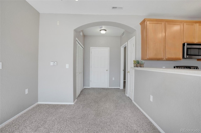 hall featuring arched walkways, baseboards, visible vents, and carpet flooring