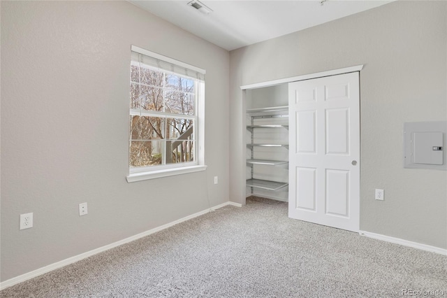 unfurnished bedroom with carpet, a closet, visible vents, electric panel, and baseboards