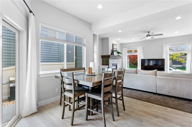 4589 Quandary Peak St, Brighton, CO 80601 - dining area with light wood-style floors, a tiled fireplace, recessed lighting, ceiling fan, and baseboards