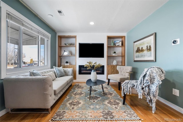 living room featuring built in features and wood-type flooring