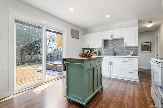 kitchen featuring white range with electric cooktop, dark hardwood / wood-style flooring, green cabinets, white cabinets, and backsplash