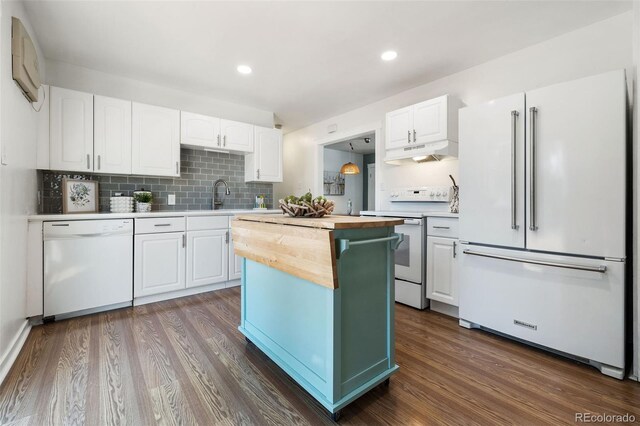 kitchen with a kitchen island, white appliances, white cabinets, and dark hardwood / wood-style floors