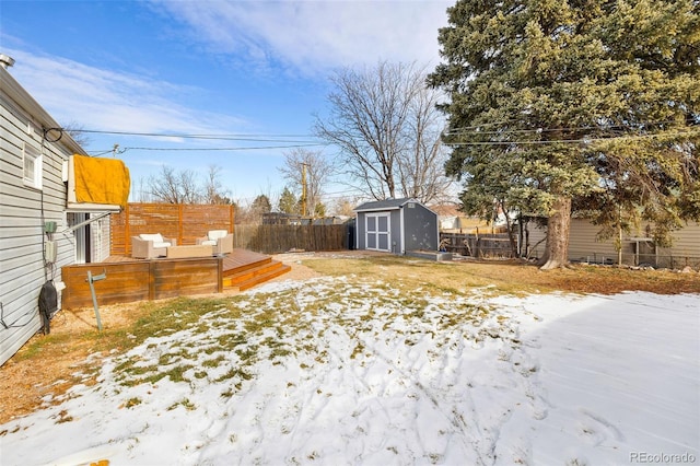 yard covered in snow featuring a deck and a storage shed