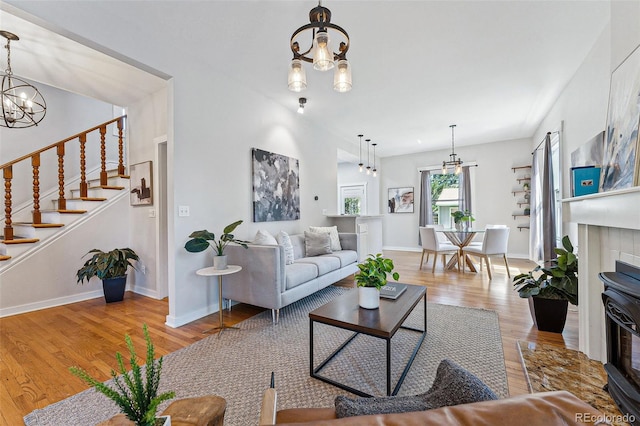 living area with a notable chandelier, stairway, baseboards, and wood finished floors