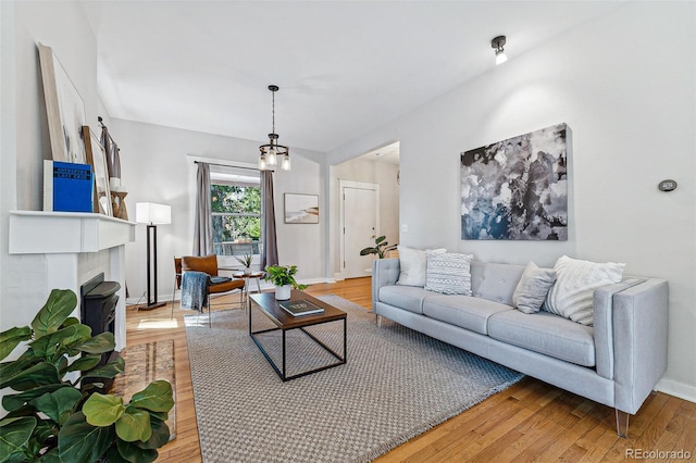 living room with baseboards, a fireplace, and light wood finished floors