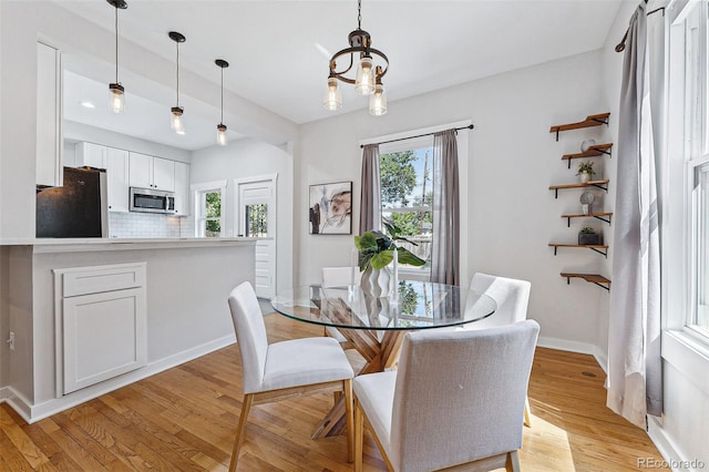 dining room featuring light wood-type flooring, baseboards, and a chandelier