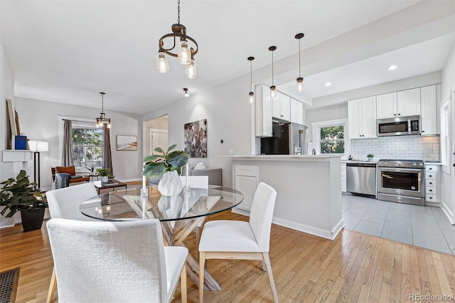 dining room with recessed lighting, light wood-type flooring, and an inviting chandelier