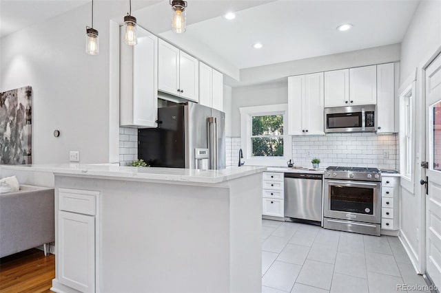 kitchen with decorative backsplash, premium appliances, a peninsula, white cabinetry, and recessed lighting