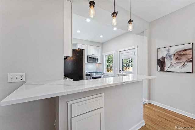 kitchen with a peninsula, light stone countertops, white cabinetry, and stainless steel appliances