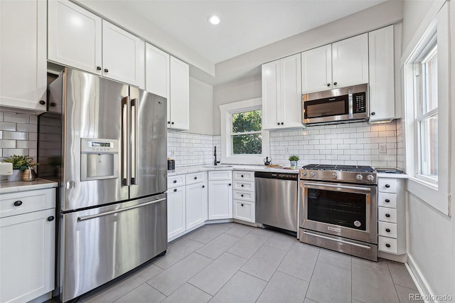 kitchen with appliances with stainless steel finishes, white cabinets, light countertops, and a sink