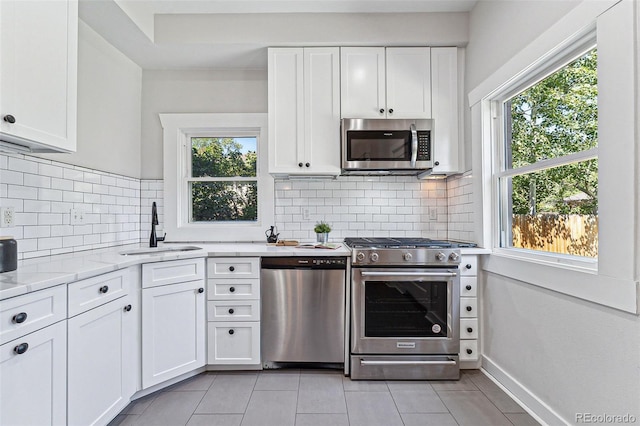 kitchen featuring appliances with stainless steel finishes, a healthy amount of sunlight, a sink, and white cabinets