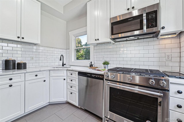 kitchen featuring light tile patterned floors, white cabinets, decorative backsplash, stainless steel appliances, and a sink