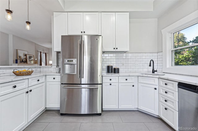 kitchen with stainless steel appliances, tasteful backsplash, a sink, and white cabinets