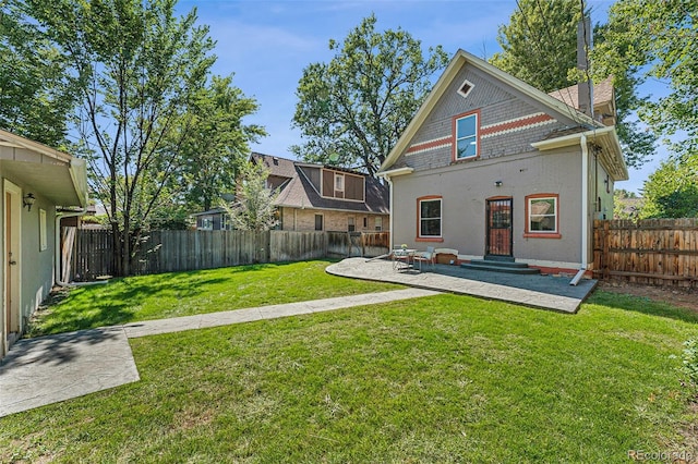 rear view of house with a patio, a lawn, and a fenced backyard